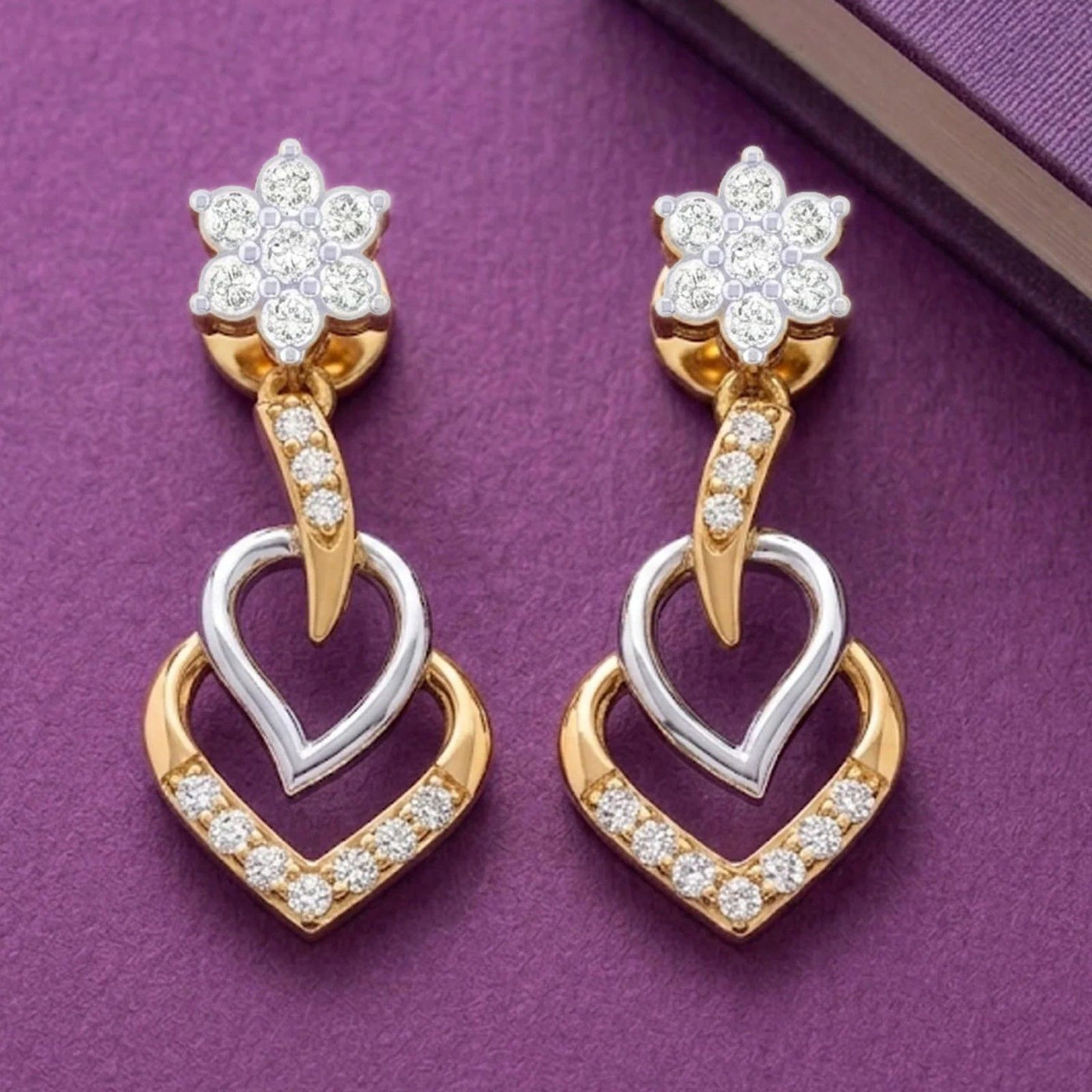 Pair of gold and diamond dangler earrings on a purple background.