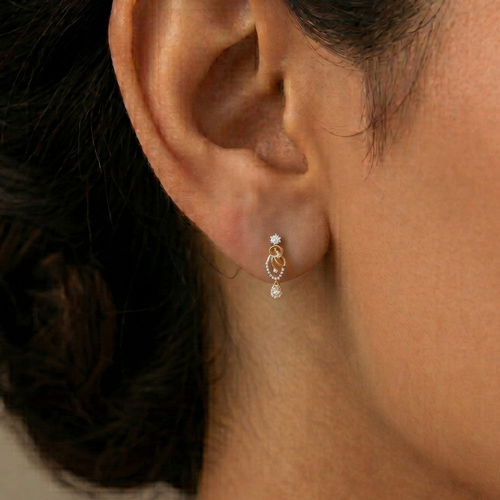 A close-up of a person's ear wearing a gold and diamond earrings with diamond accents.