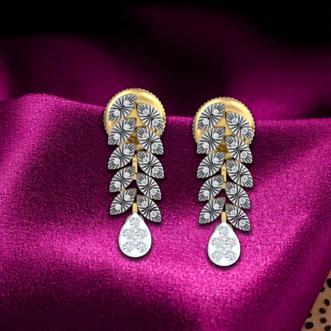 A pair of gold and diamond dangler earrings and teardrop-shaped, displayed on a draped magenta satin fabric.