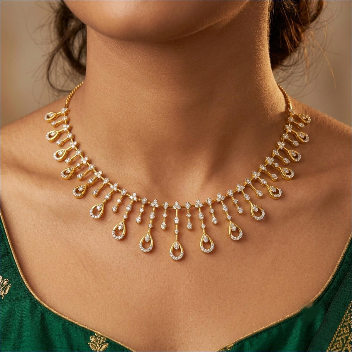 Gold teardrop pendant necklace with clear stones, worn by a model in a green embroidered saree.