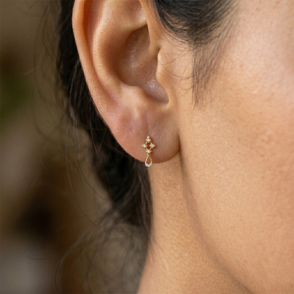 Close-up shot of a gold geometric dangle earrings with open teardrop bottoms and diamond accents earring