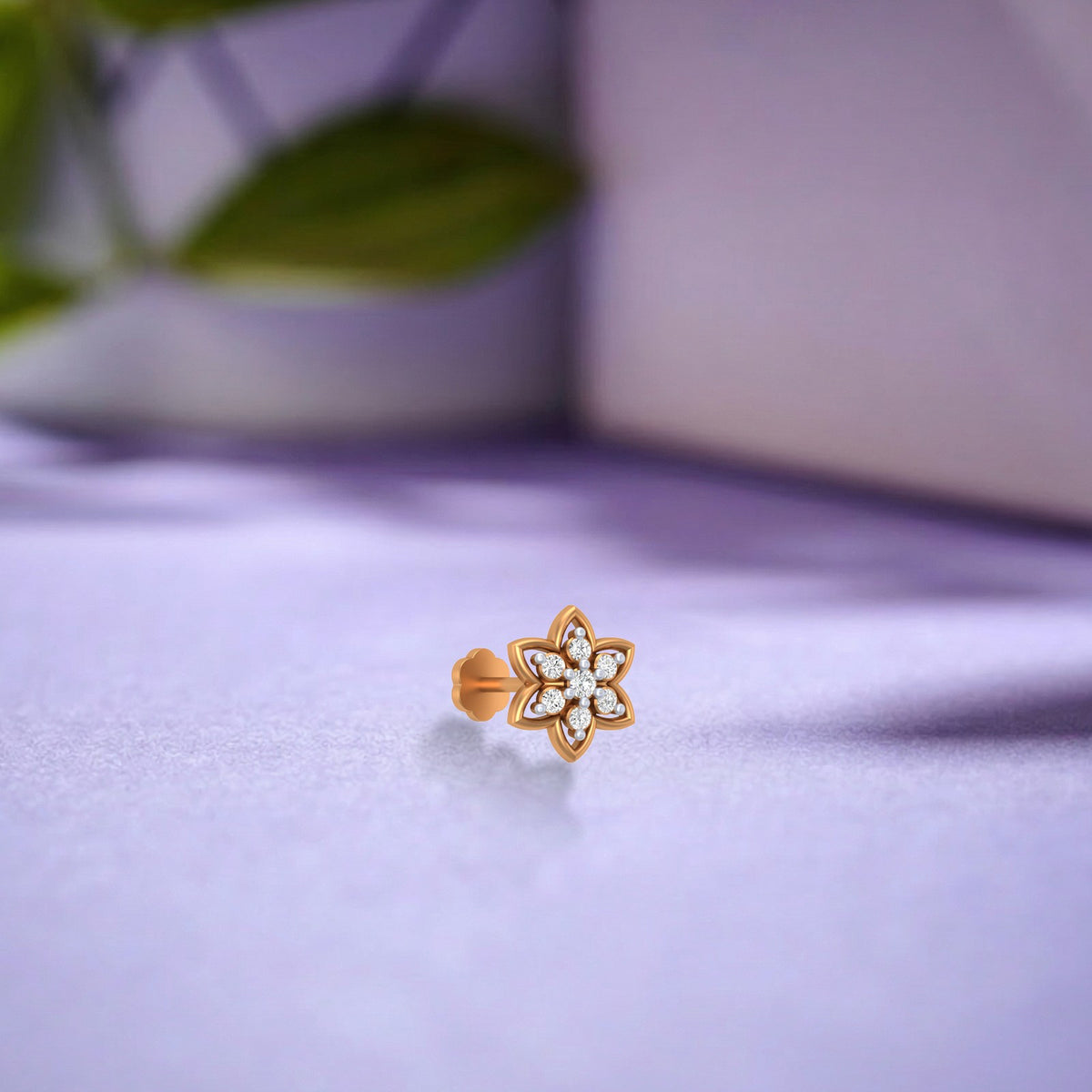Gold and diamond floral nose pin on a purple surface. 