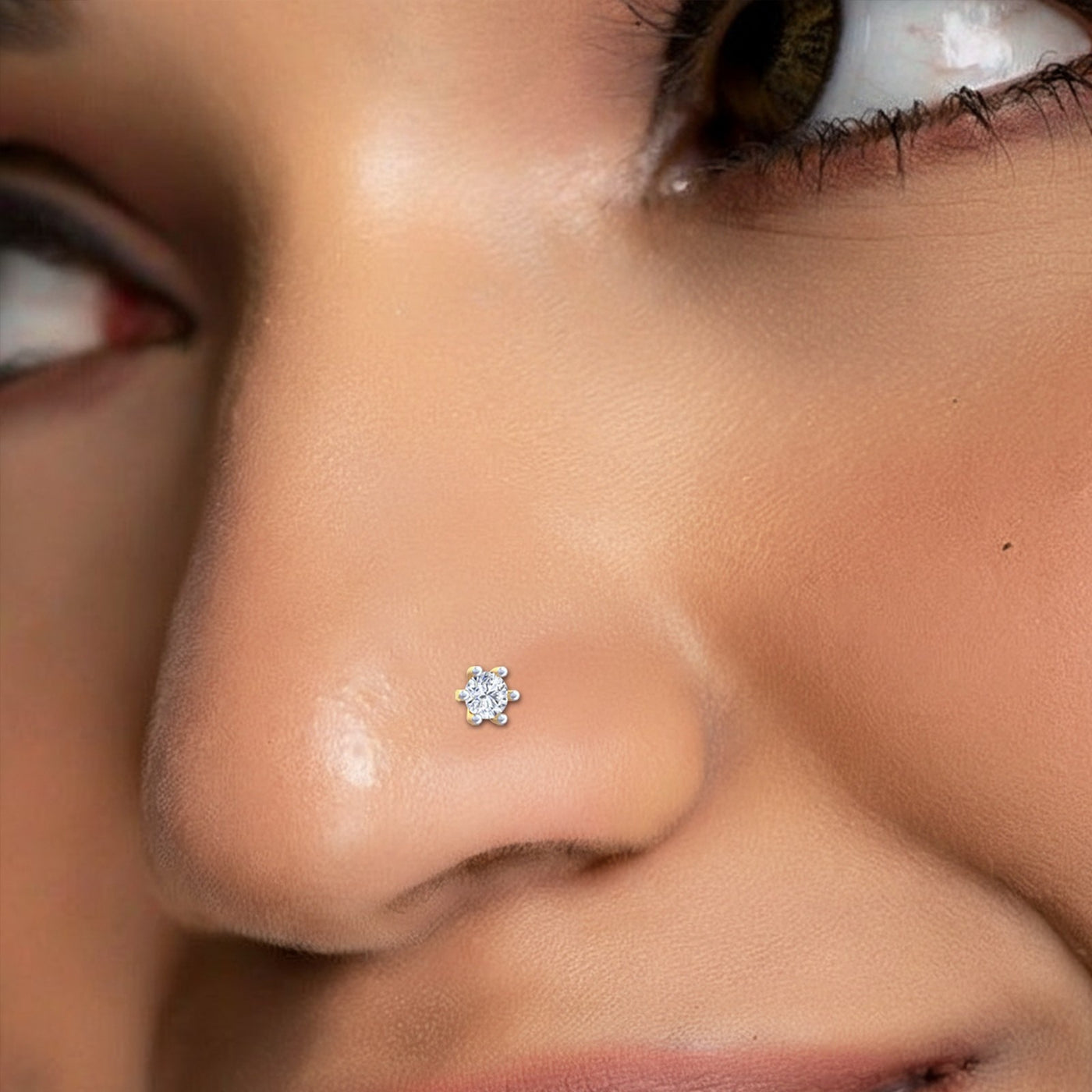 A close-up of a person's nose wearing a small circular stud earring with a silver-toned metal border and clear stones.