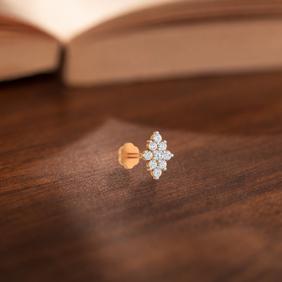 gold and diamond cluster nose ring against a wooden surface.