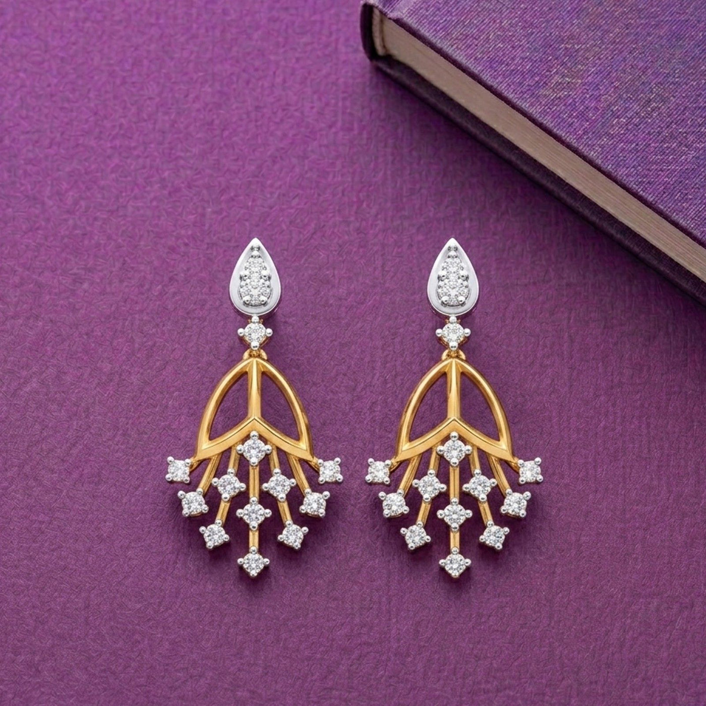 A pair of gold and diamond drop earrings featuring a tiered floral design on a purple background