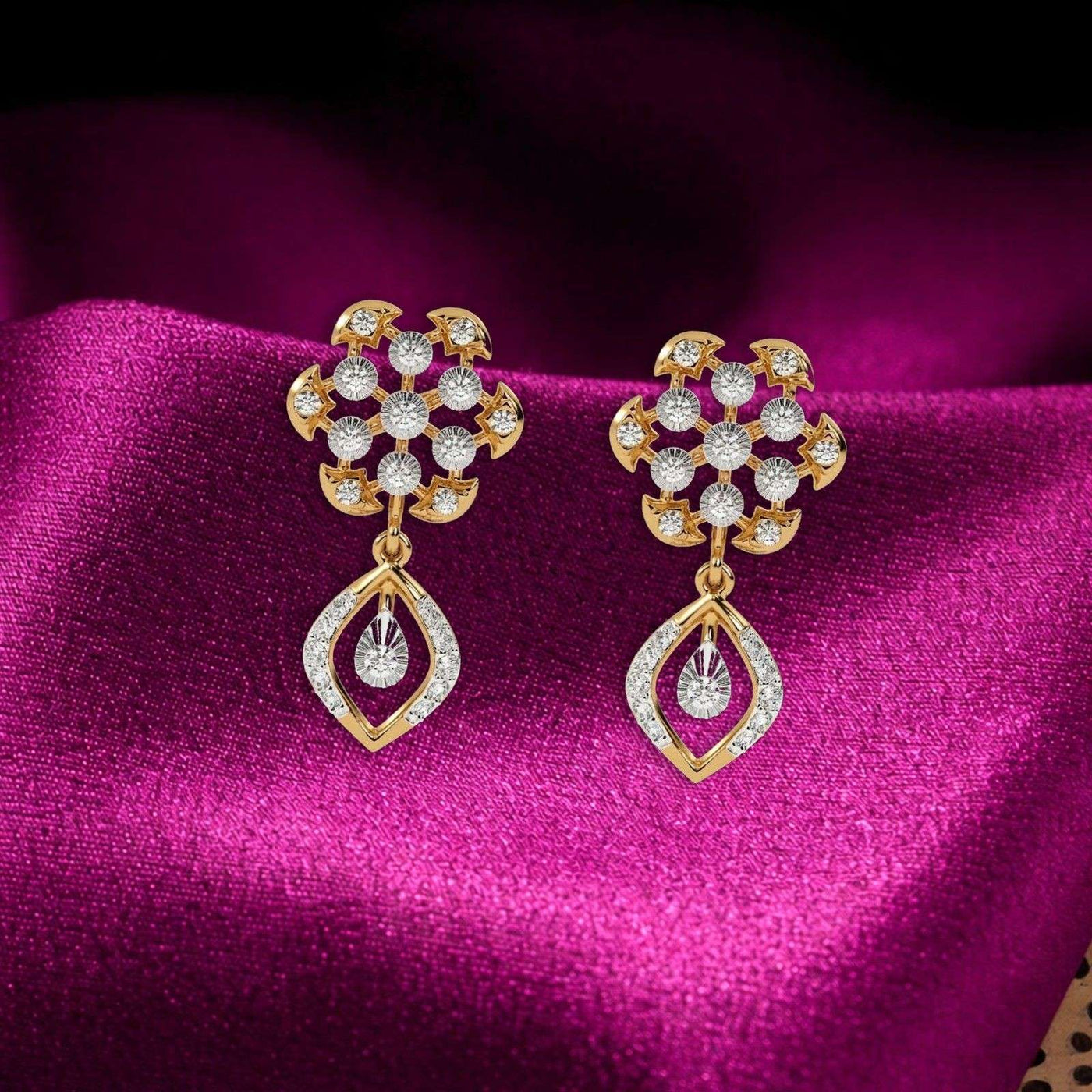 A pair of gold-plated dangle earrings with teardrop design, displayed on a rich magenta satin fabric background.