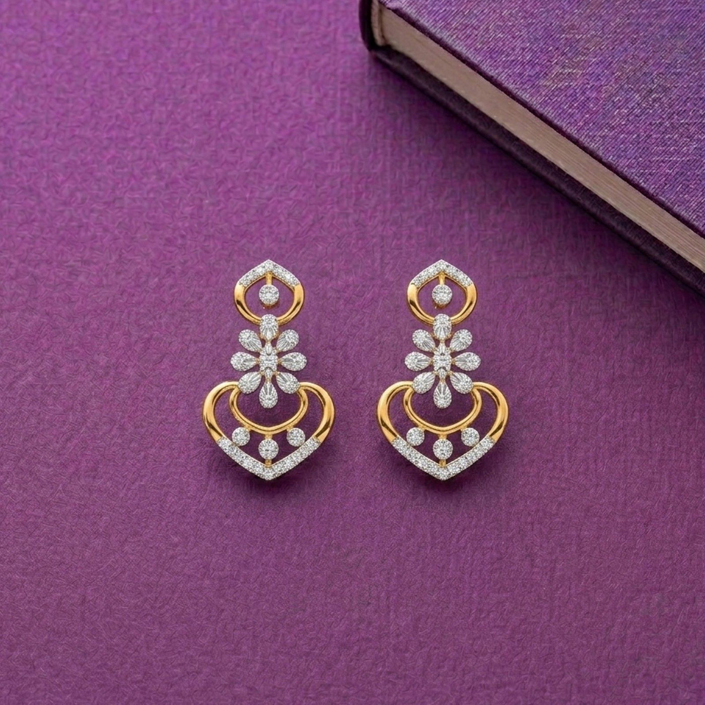 A pair of elegant gold earrings with intricate floral and heart-shaped designs