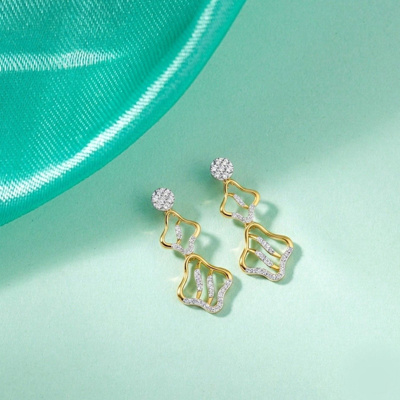A pair of gold earrings with diamond accents, featuring an elegant, intricate design.