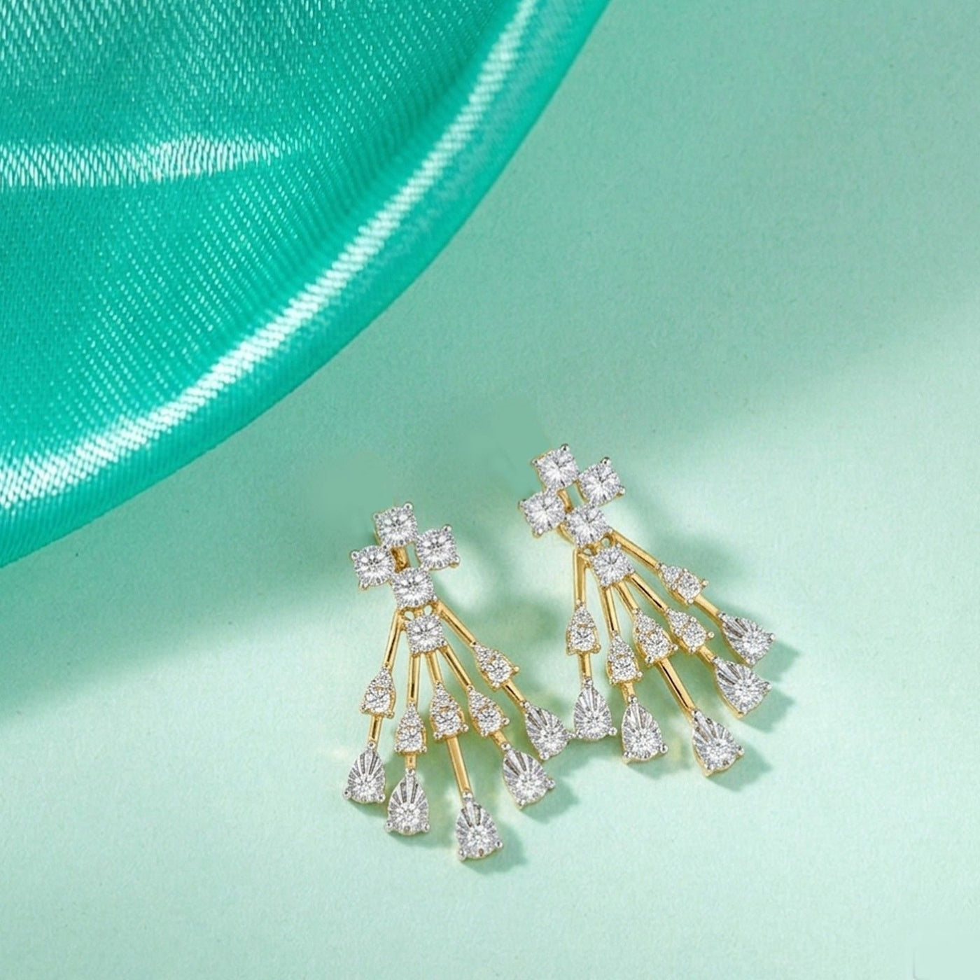 Gold and diamond chandelier earring on a blue background.