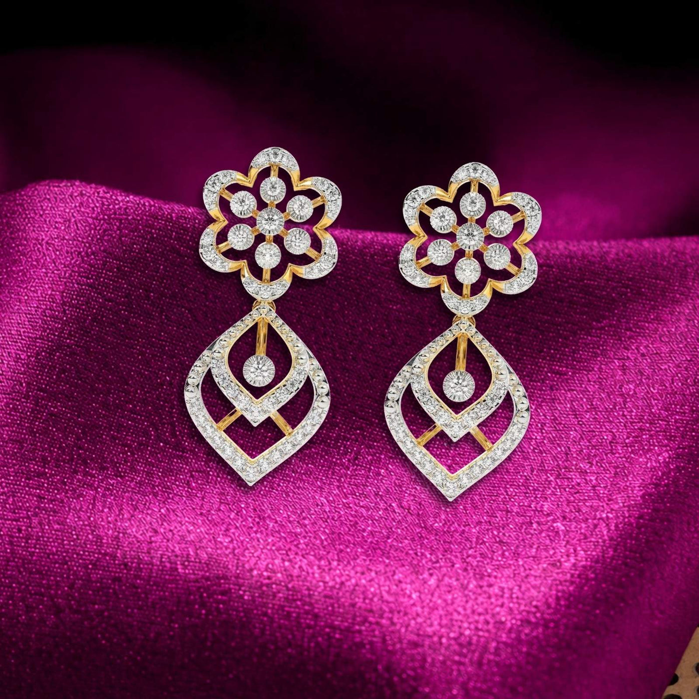 Gold and diamond dangler stud earrings on a magenta fabric background