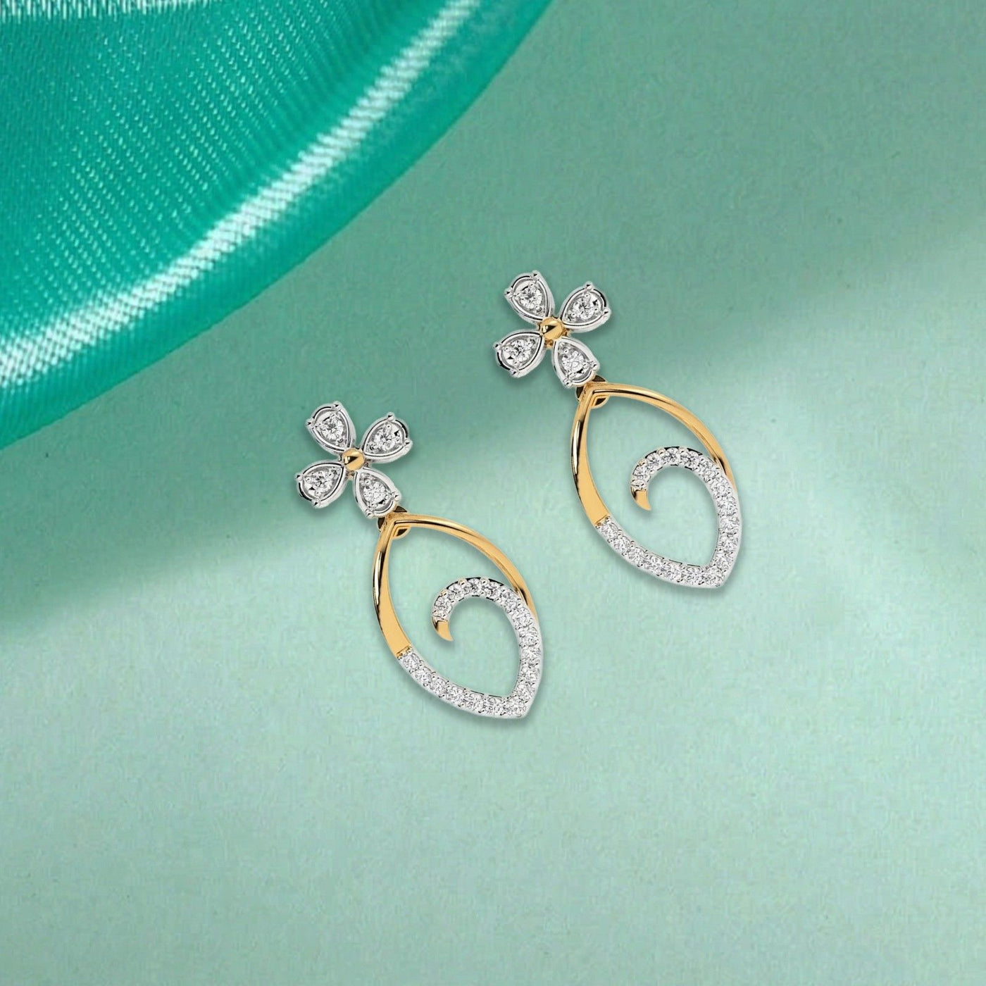 A pair of gold earrings with diamond accents, featuring a floral design on top and a teardrop shape with diamonds encircling the lower part.