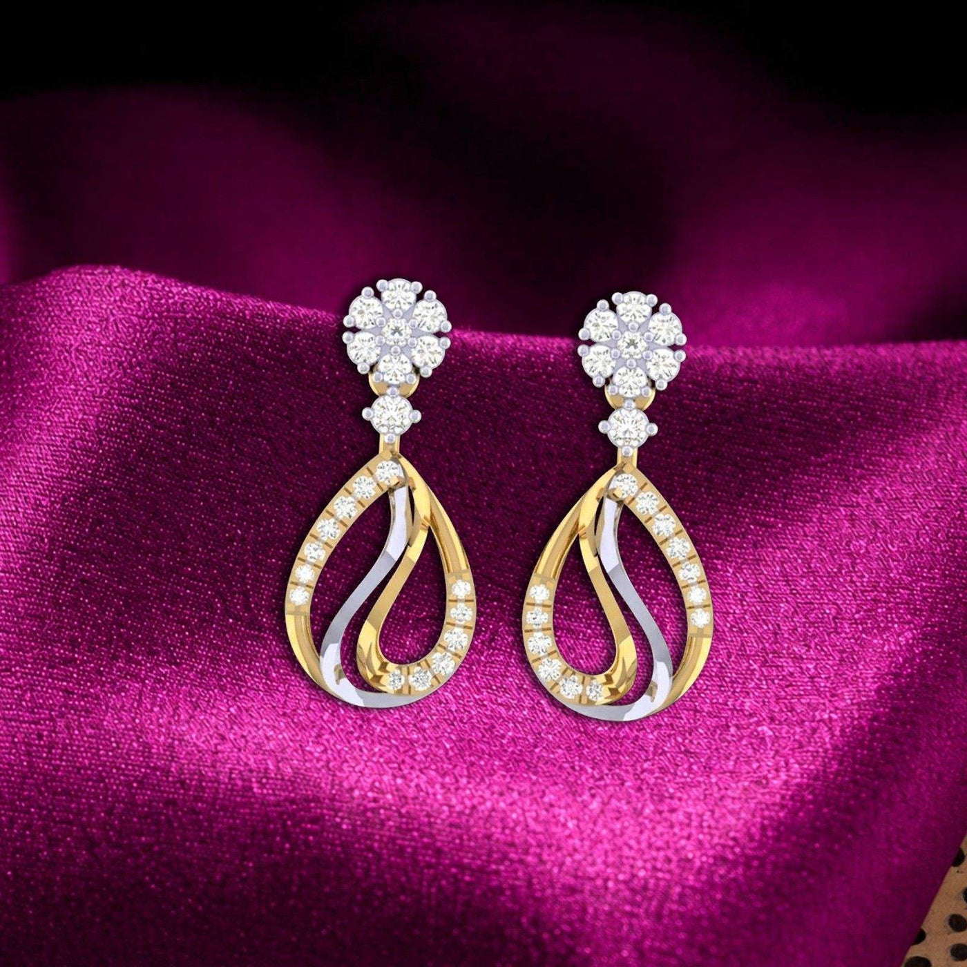 Elegant two-tone gold and diamond drop earrings resting on draped magenta satin