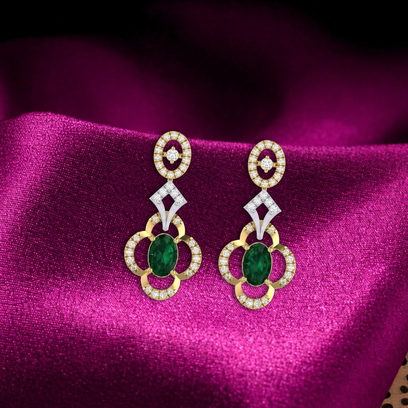 A pair of gold and diamond drop earrings featuring an oval green gemstone, resting on a draped magenta fabric background