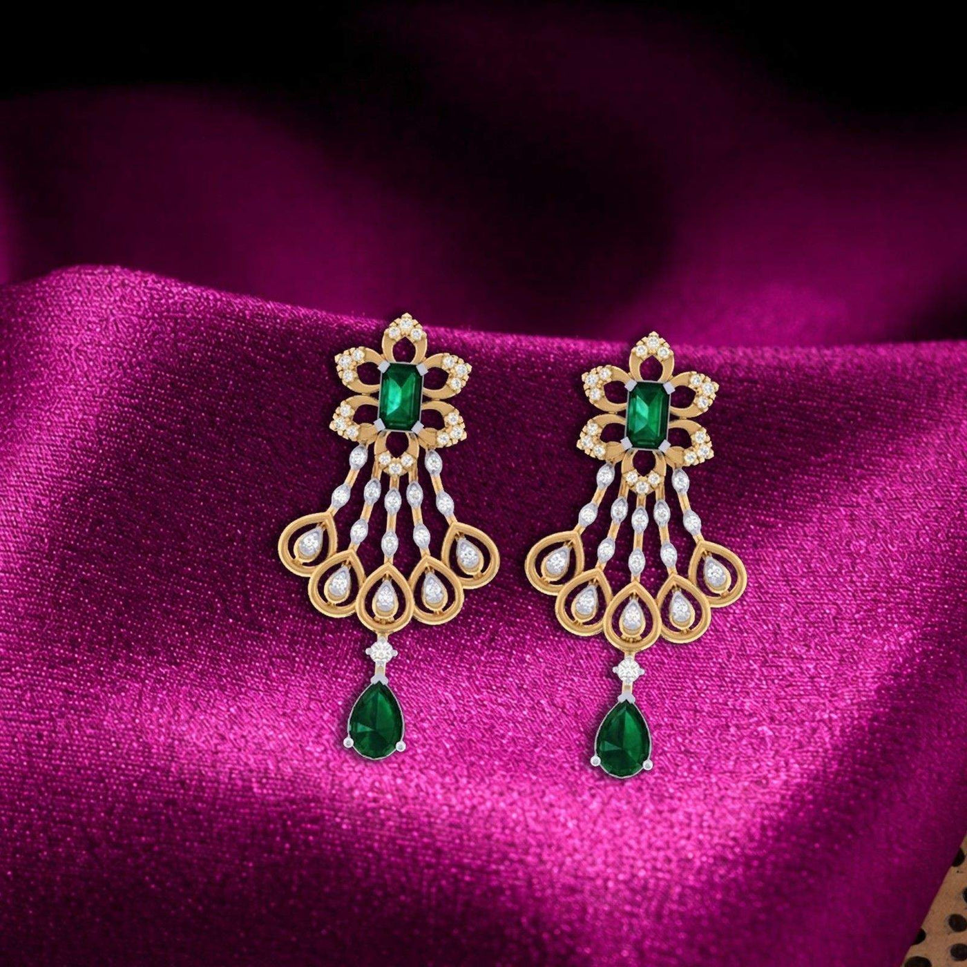 Pair of chandelier gold earrings with green gemstones, displayed on a rich magenta satin fabric.