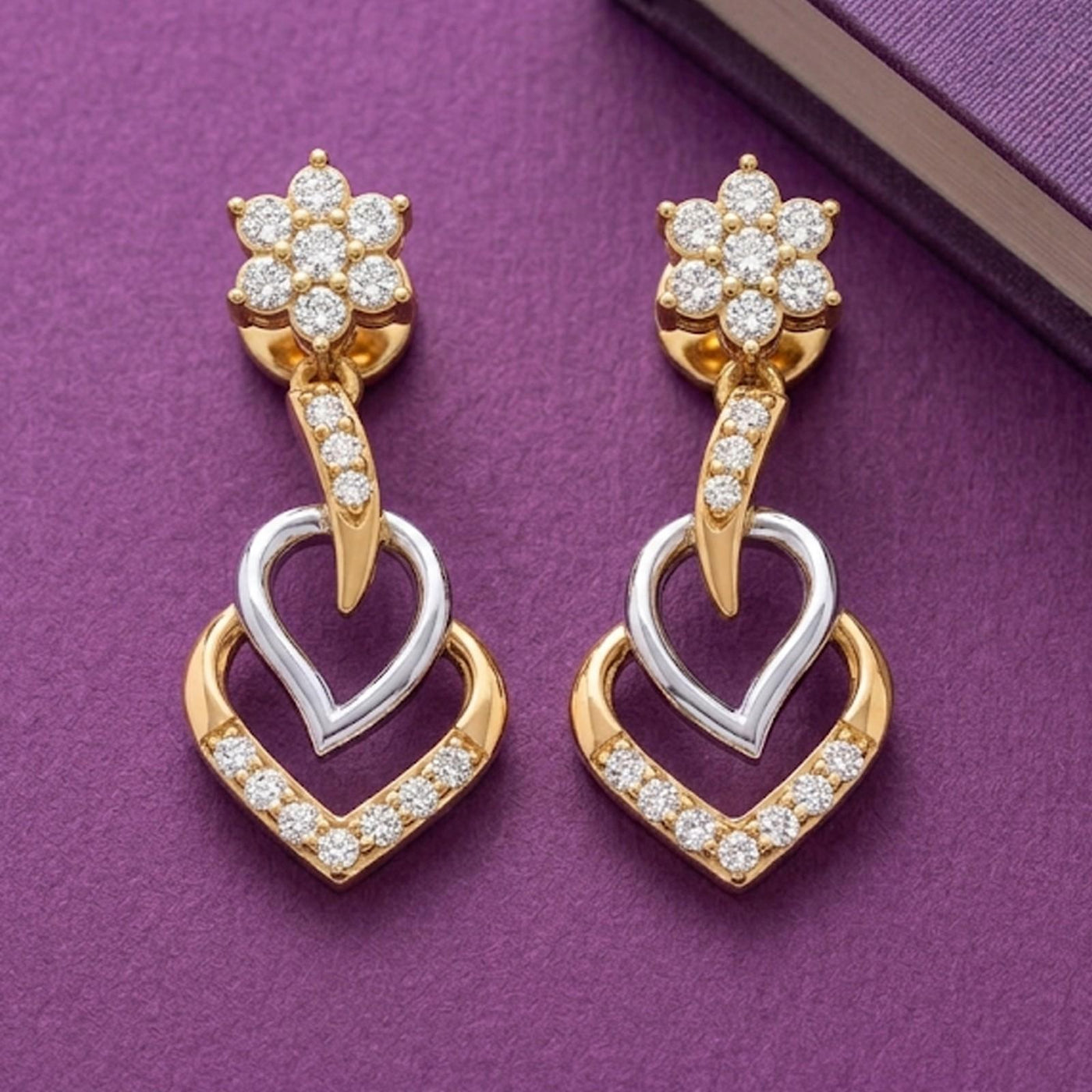 Pair of gold and diamond dangler earrings on a purple background.