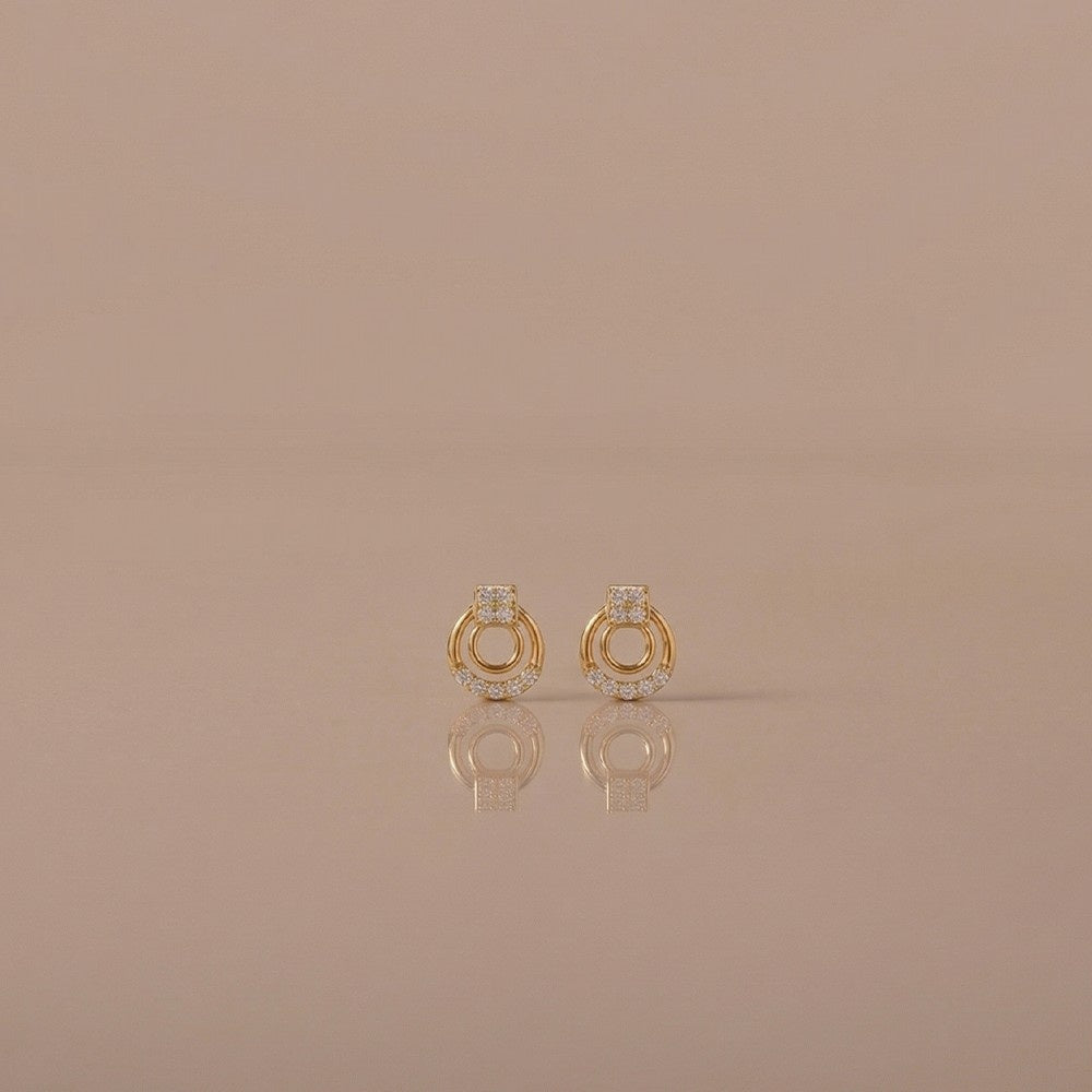 Gold and diamond stud earrings on a beige background.