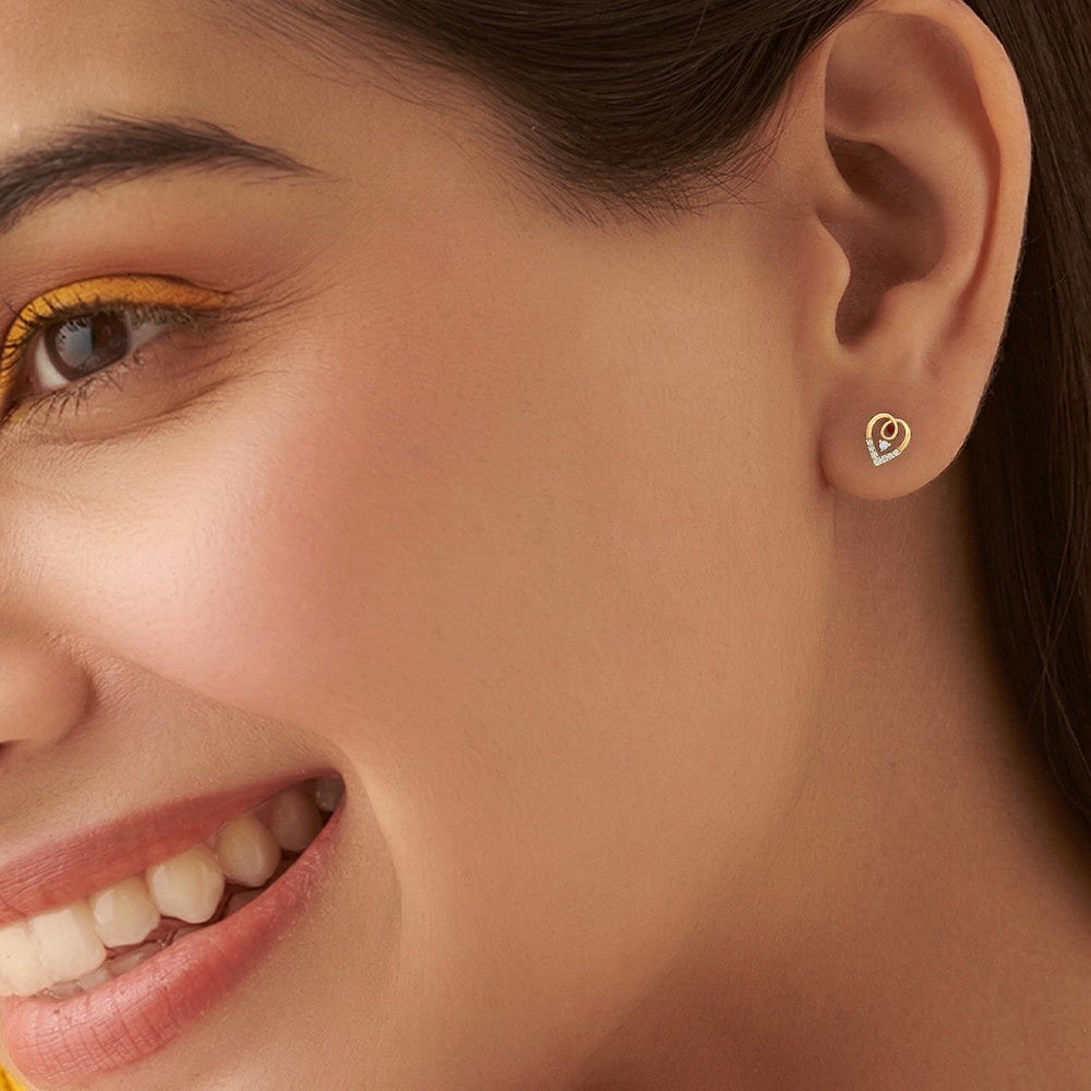 Close-up of a woman wearing a gold and diamond heart-shaped earring.