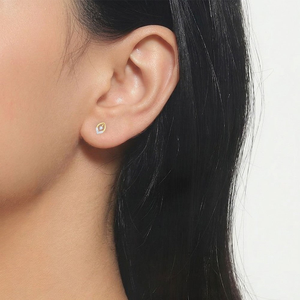 Close-up of an ear wearing a gold and diamond earring on a neutral background.
