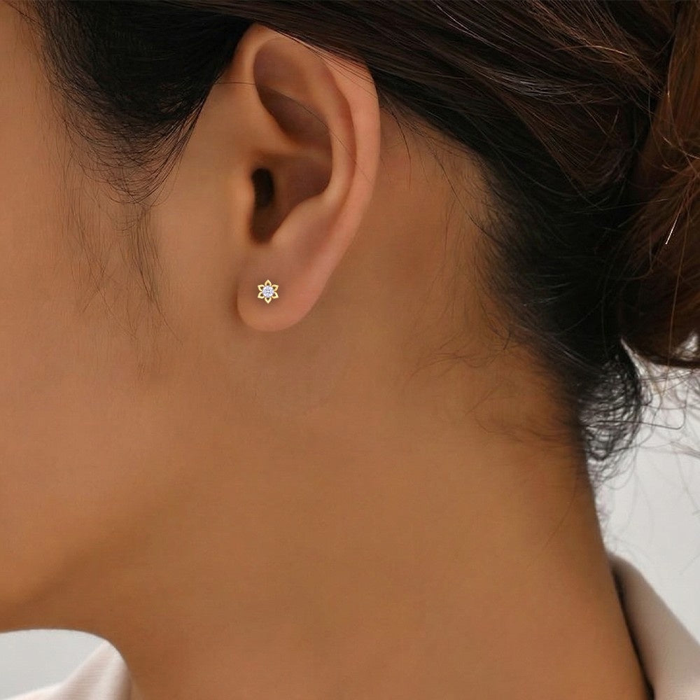 Close-up of an ear wearing a gold earring with a floral design.