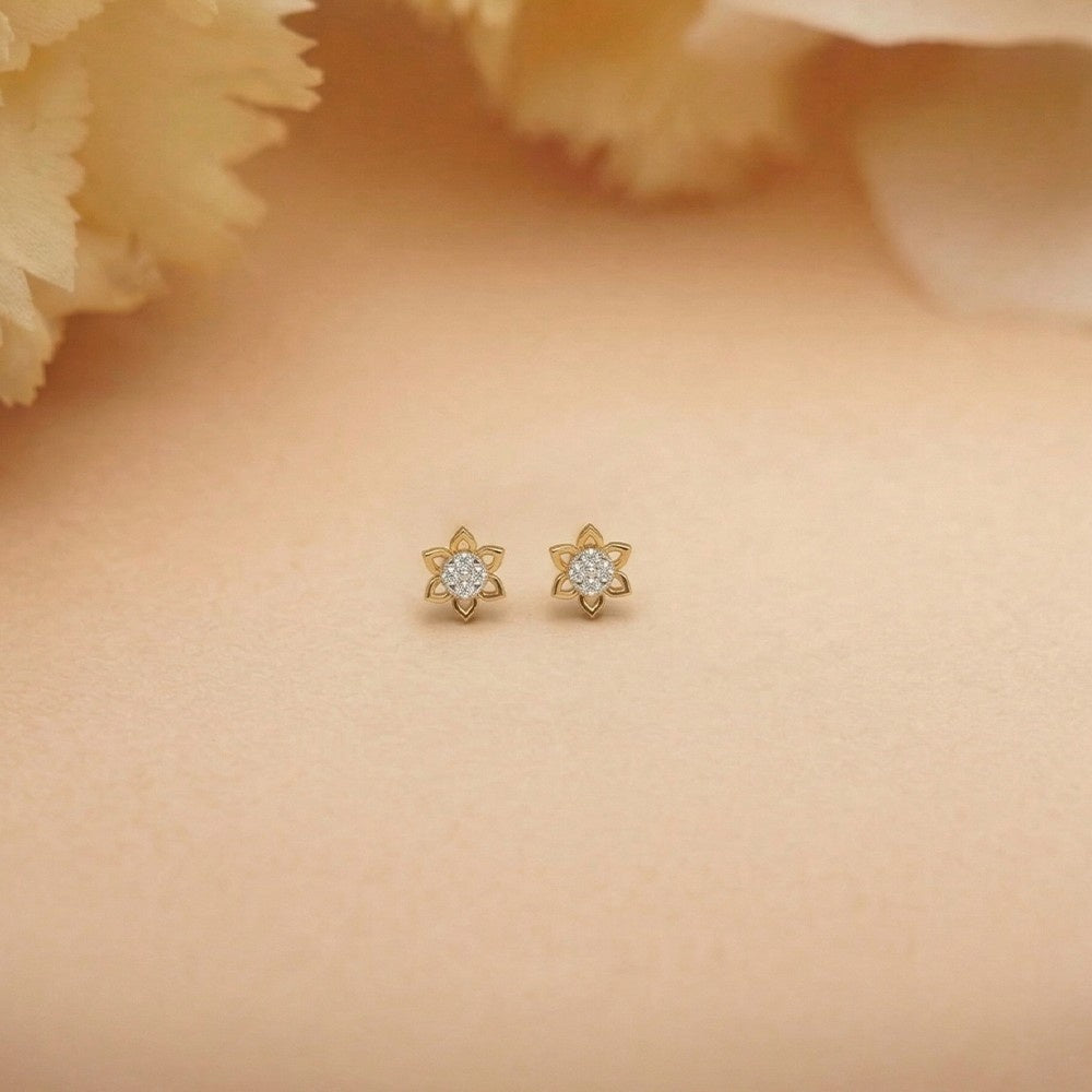 Gold and diamond floral earrings on a beige background.