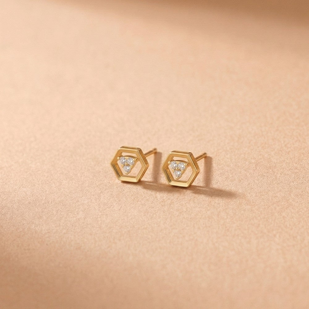 Gold and diamond stud earring on a pink background.