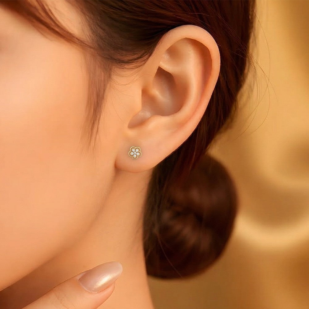 Close-up of an ear wearing a floral stud earring with a blurred background.