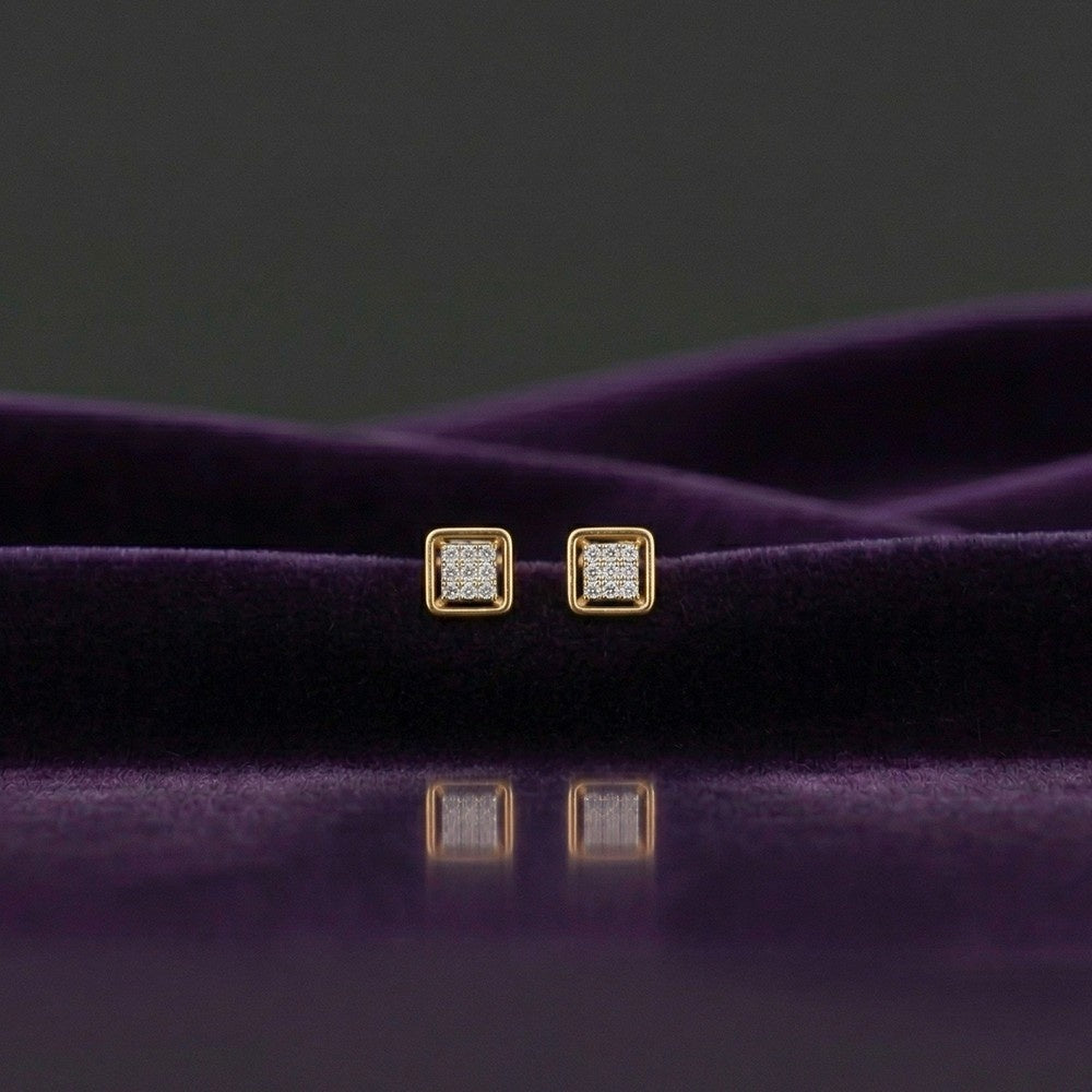 Gold square-shaped stud earrings on a purple surface.