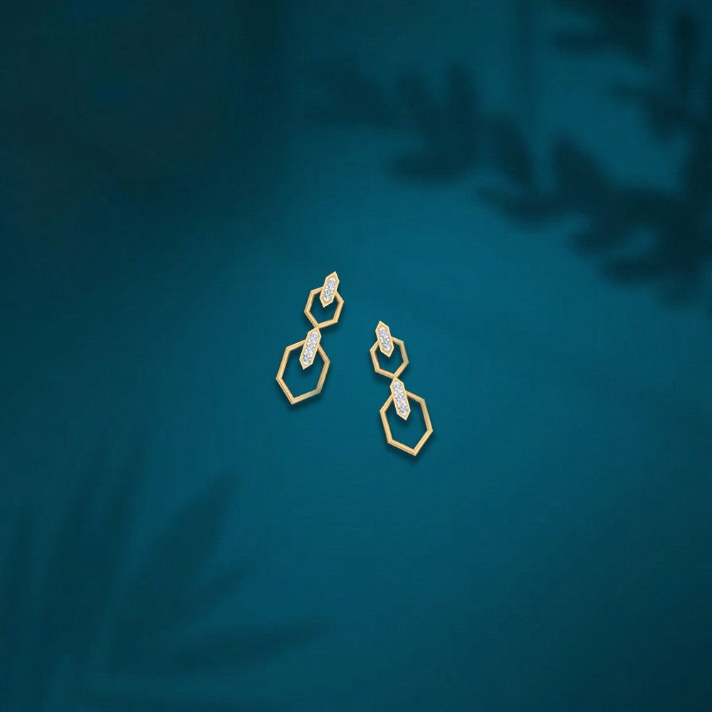 Gold an diamond drop earring on a teal backgound.