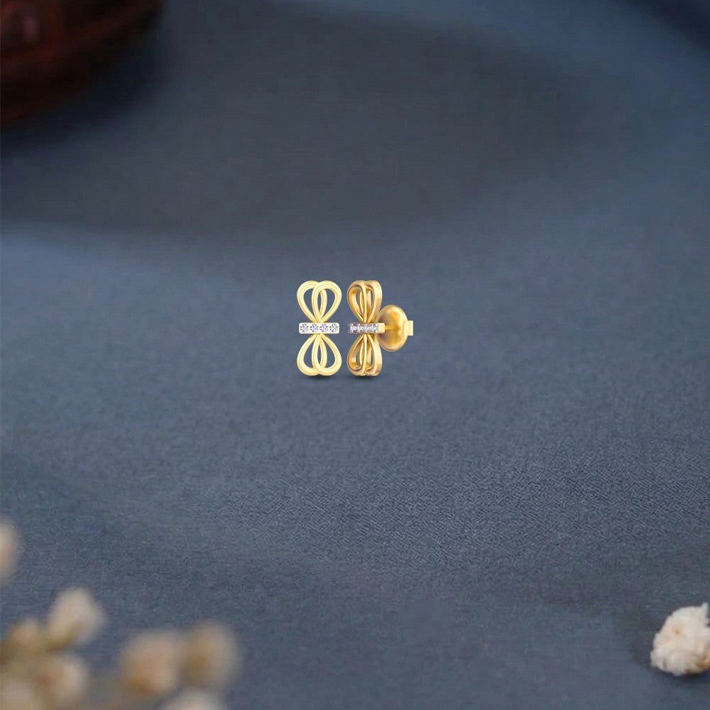 Gold and diamond bow stud earring on a blue surface.