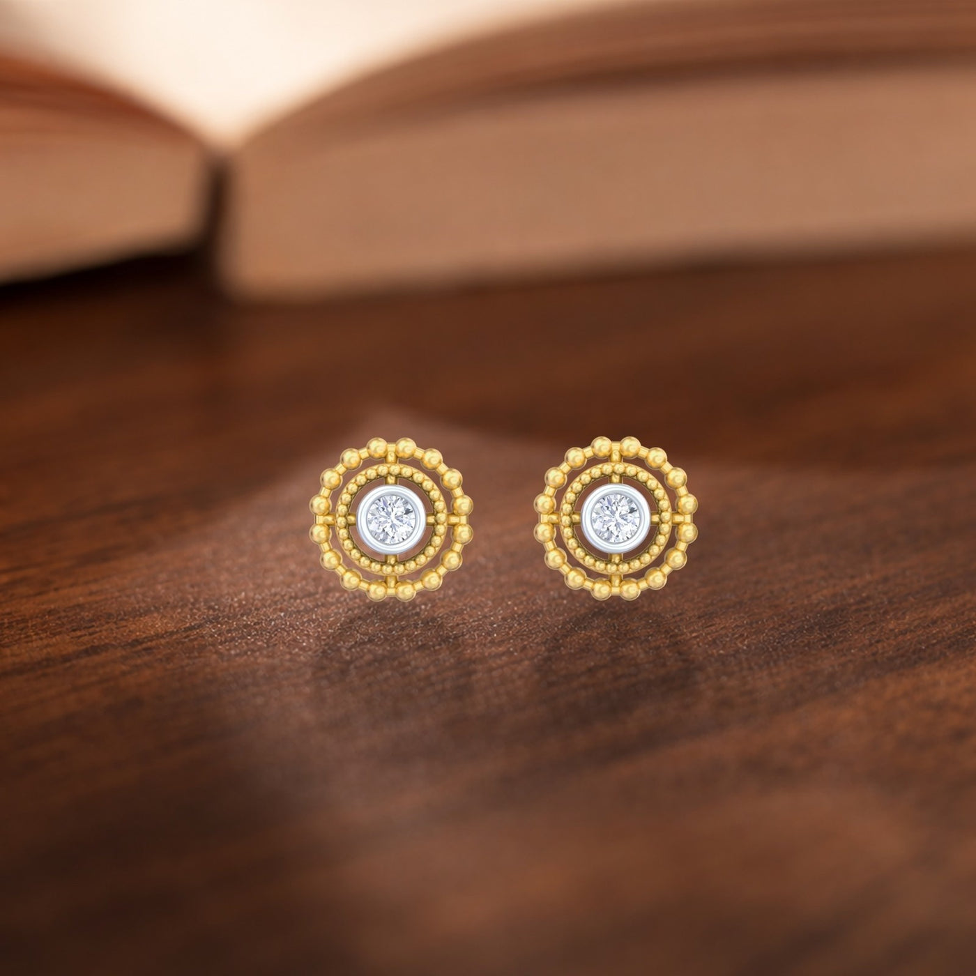 A pair of two-tone gold stud earrings featuring a central round diamond surrounded by beaded gold.