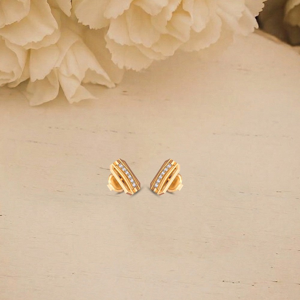 Gold and diamond stud earrings on a beige surface.