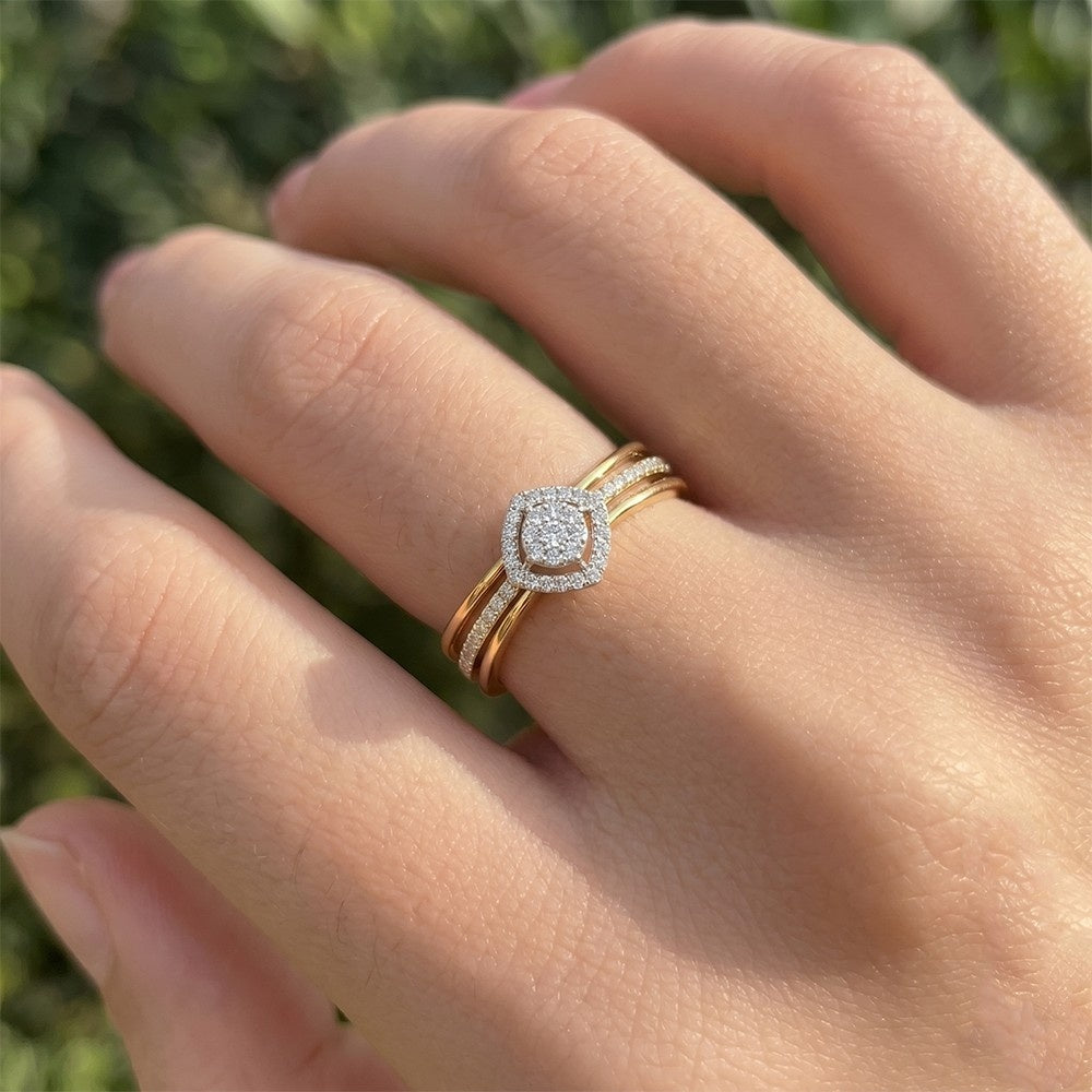 Hand wearing two diamond rings with a blurred green background