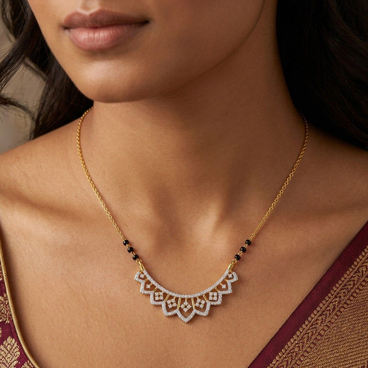A close-up of a woman wearing a delicate gold mangalsutra with a scalloped white crystal mangalsutra and small black bead accents.
