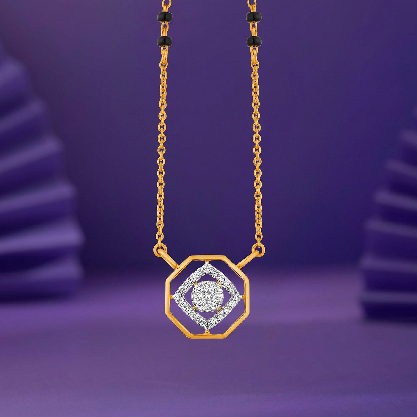 A gold mangalsutra with a geometric octagonal design, featuring a central diamond-shaped cluster of clear stones, displayed against a purple background.