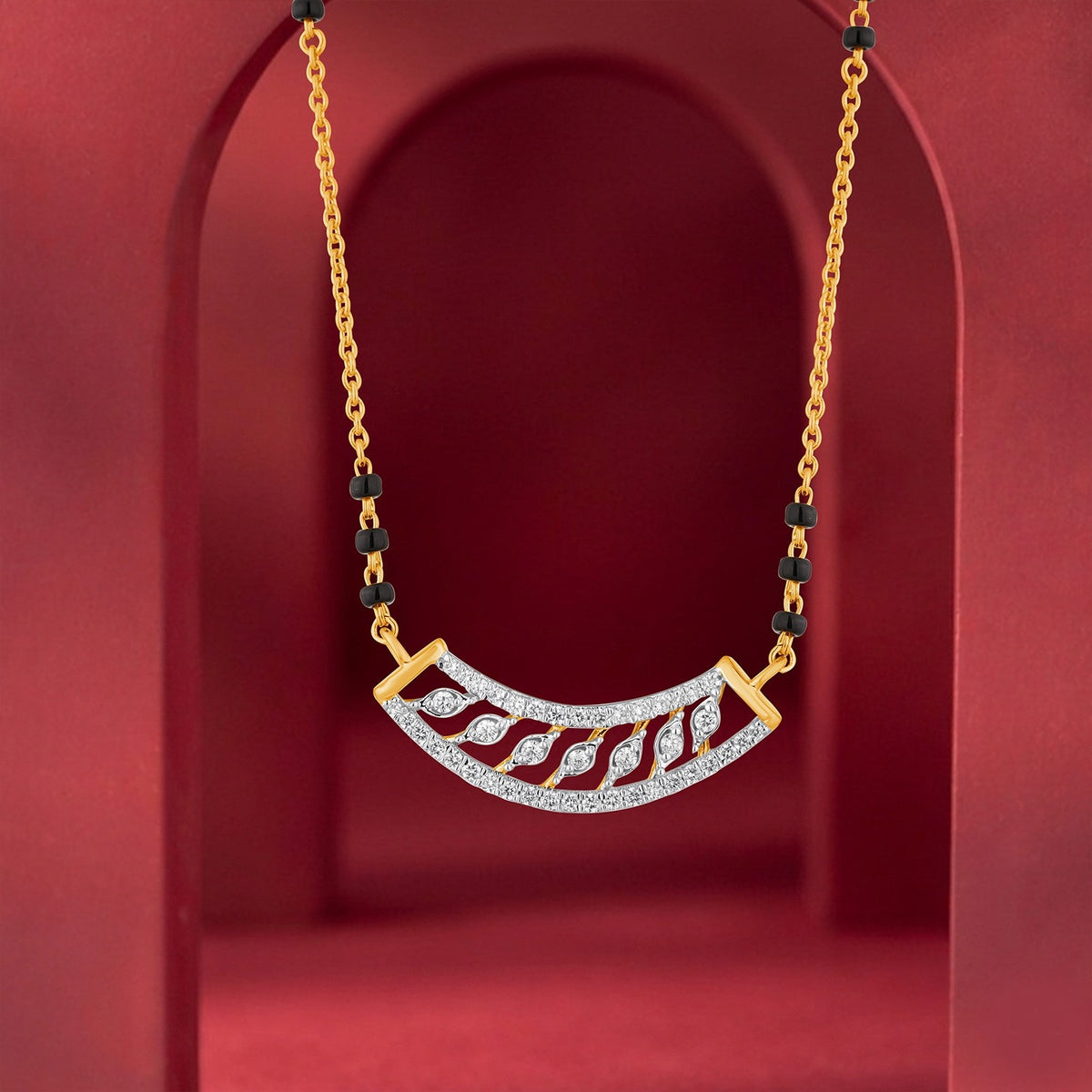 Gold mangalsutra with a curved white pavé mangalsutra featuring red inlay, displayed against a red arched background.