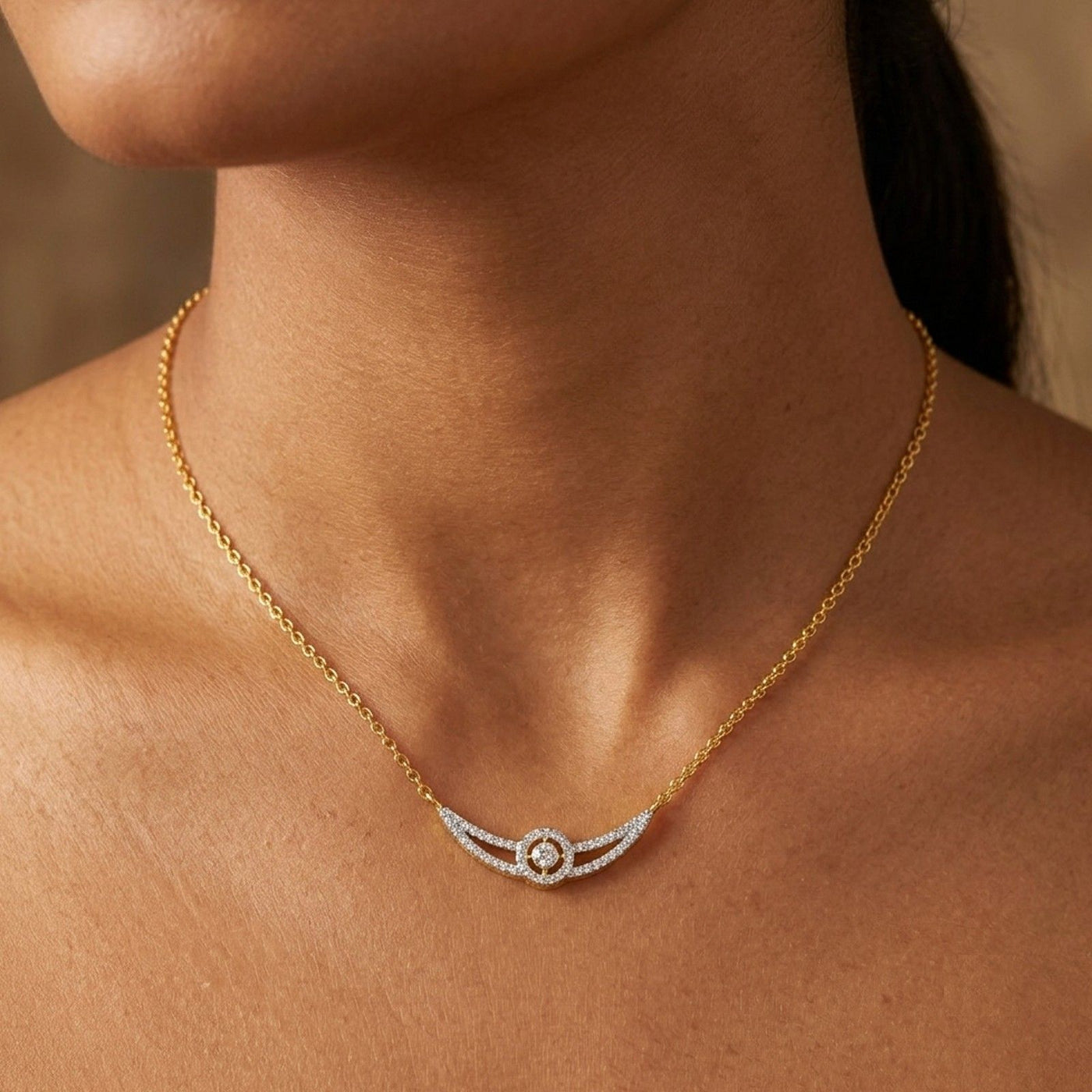 A close-up of a model's neck and upper chest wearing a delicate gold chain mangalsutra with a curved wing-shaped with small clear stones.