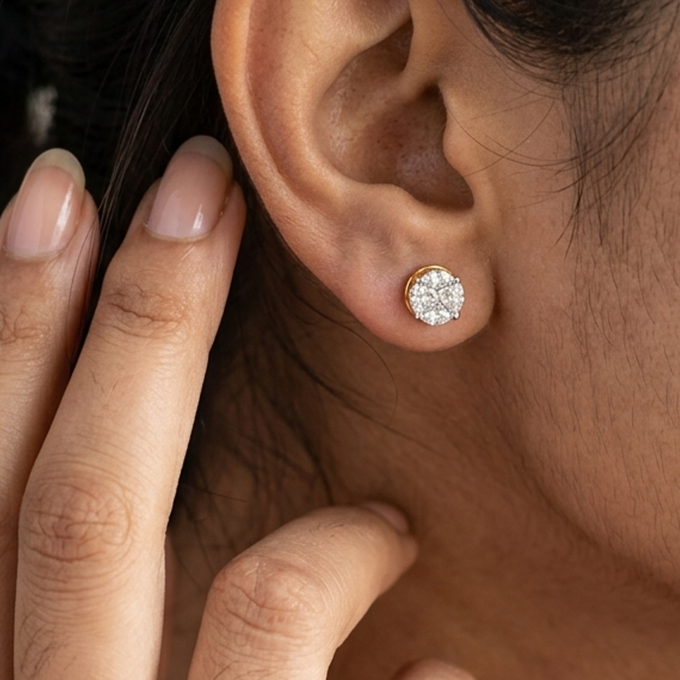 Women wearring a gold and diamond round stud earrings