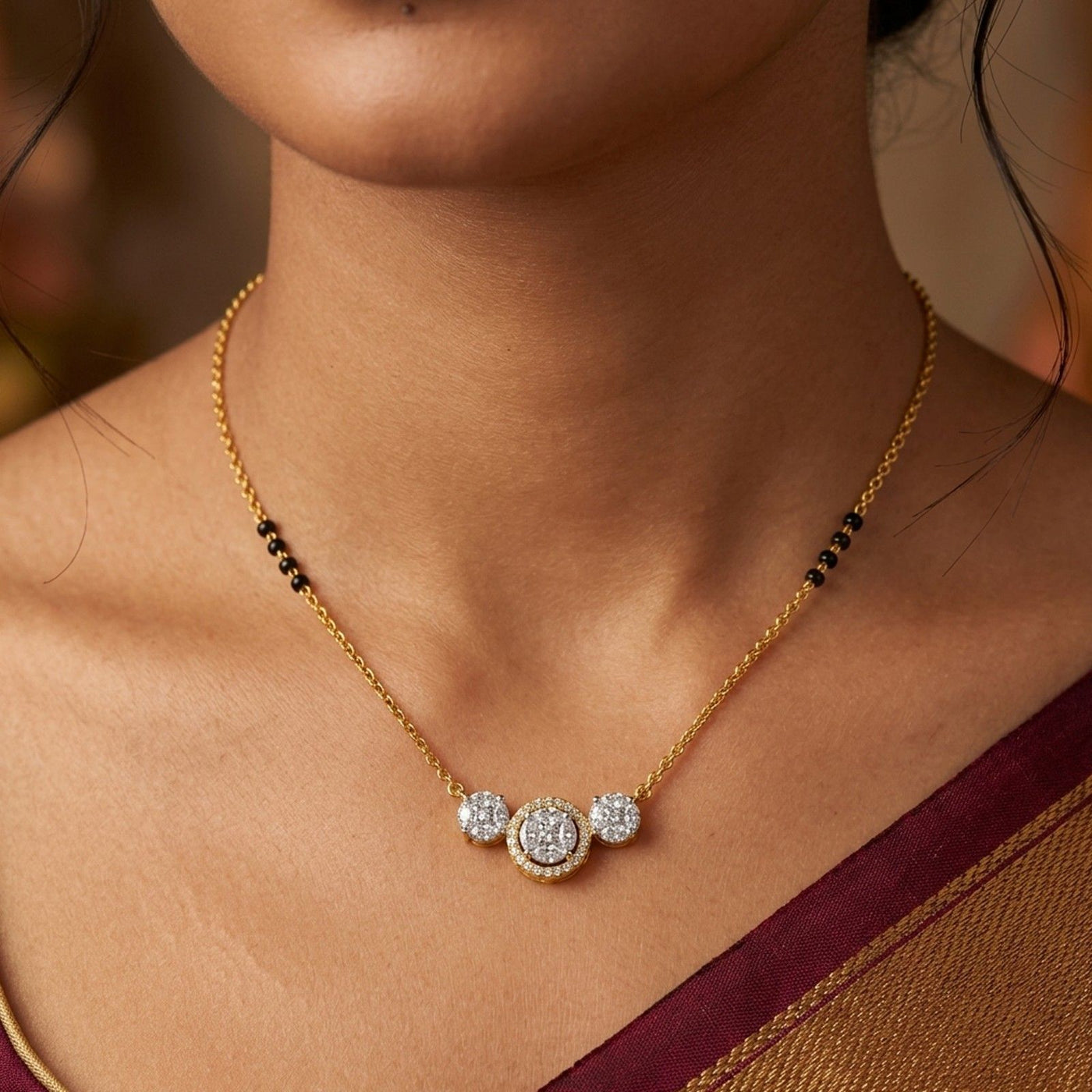 A close-up of a woman wearing a delicate gold mangalsutra with three circular diamond mangalsutra and small black bead accents on the chain.