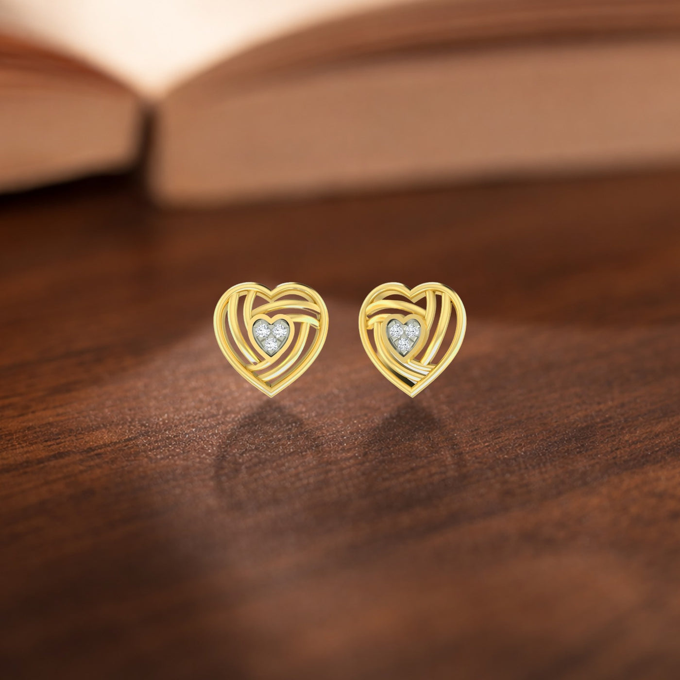 Gold and diamond heart-shaped stud earrings on a wooden surface. 