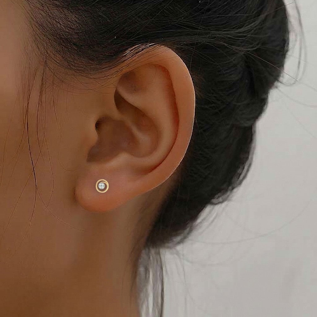 Close-up shot of a gold and diamond stud earrings with circular design.