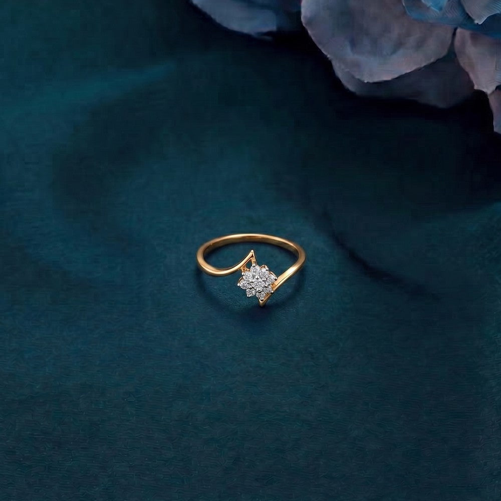 Gold and diamond with floral-design cluster setting on a teal surfae.