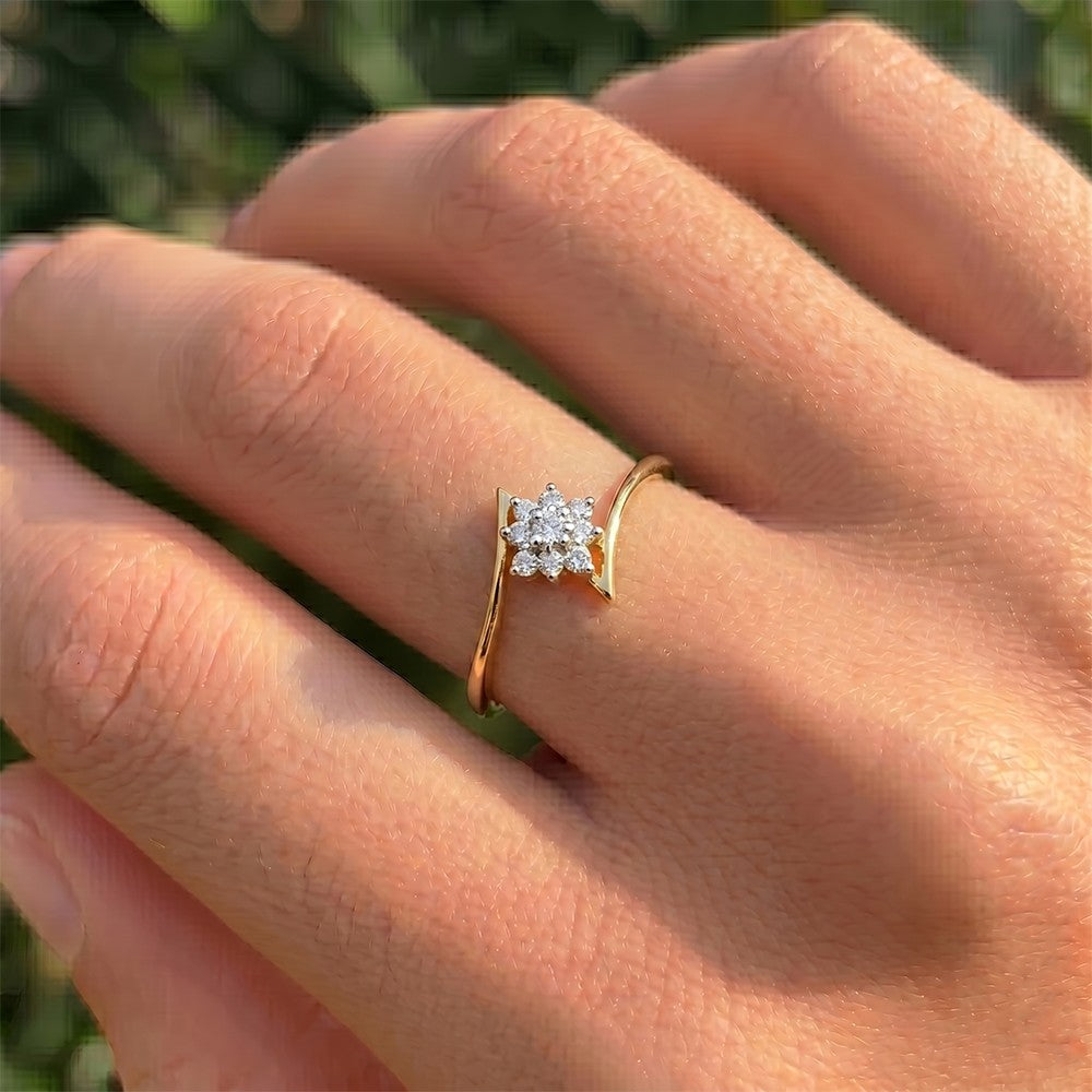 Gold and diamond with floral-design cluster setting on a person's finger.