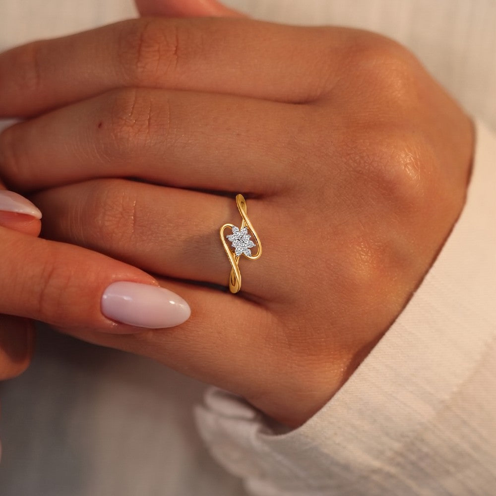 Gold and diamond with floral-design cluster setting on a person's finger.