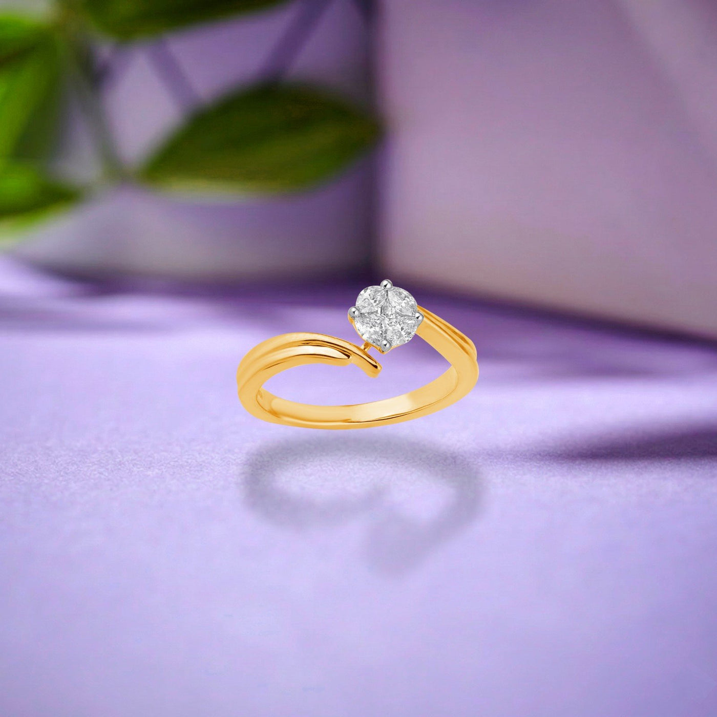 A gold ring with a round-cut clear gemstone, displayed on a soft purple surface with a blurred background.
