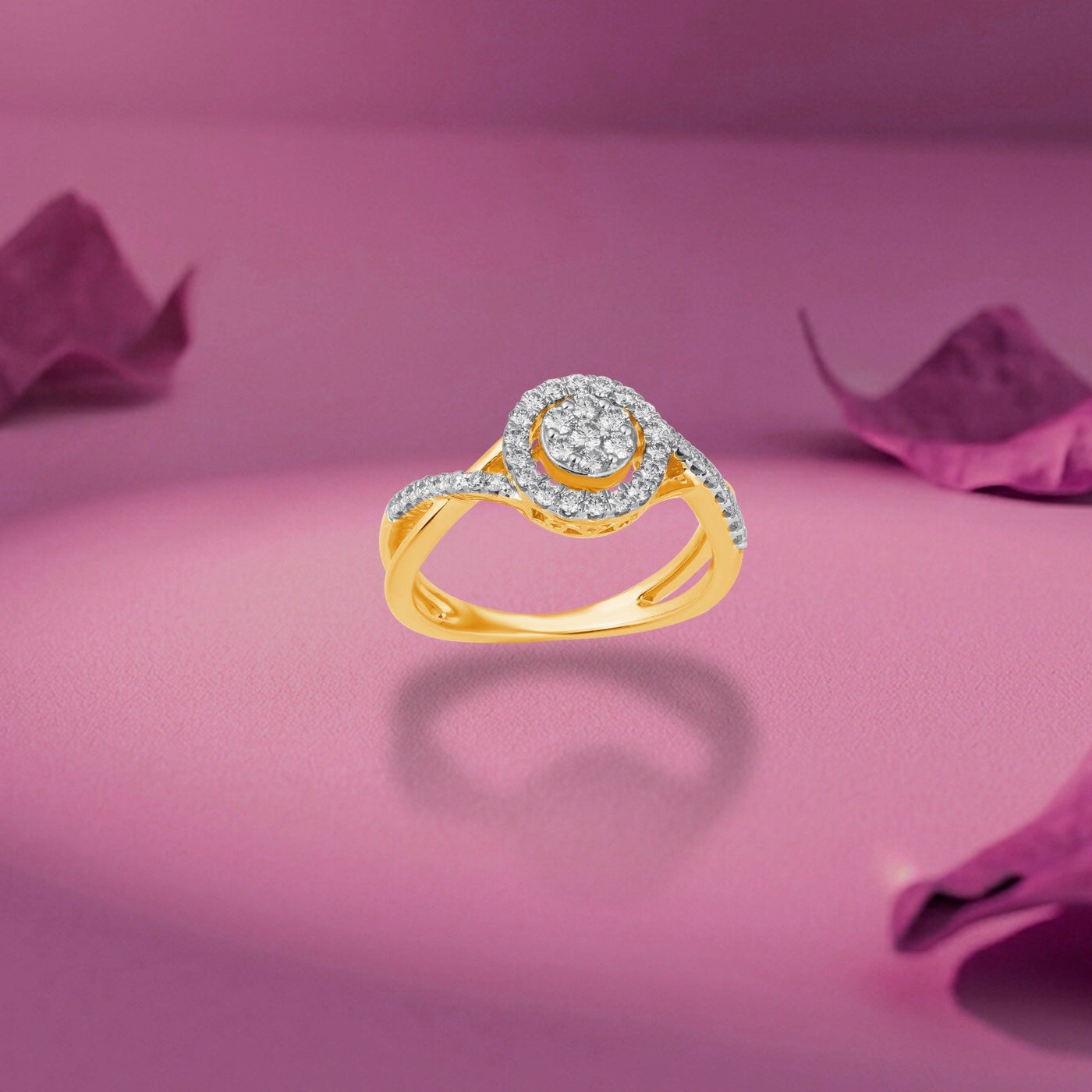 Gold ring featuring a round diamond cluster with a halo design, shown on a pink surface.
