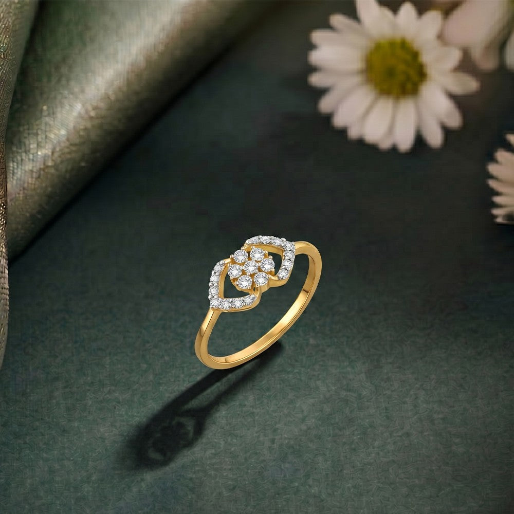 A gold ring featuring a floral design cluster at the center, shown on a green surface.