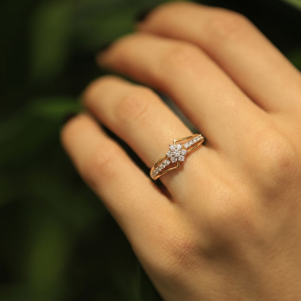 Gold ring featuring a central floral-shaped cluster, shown on a person's finger.