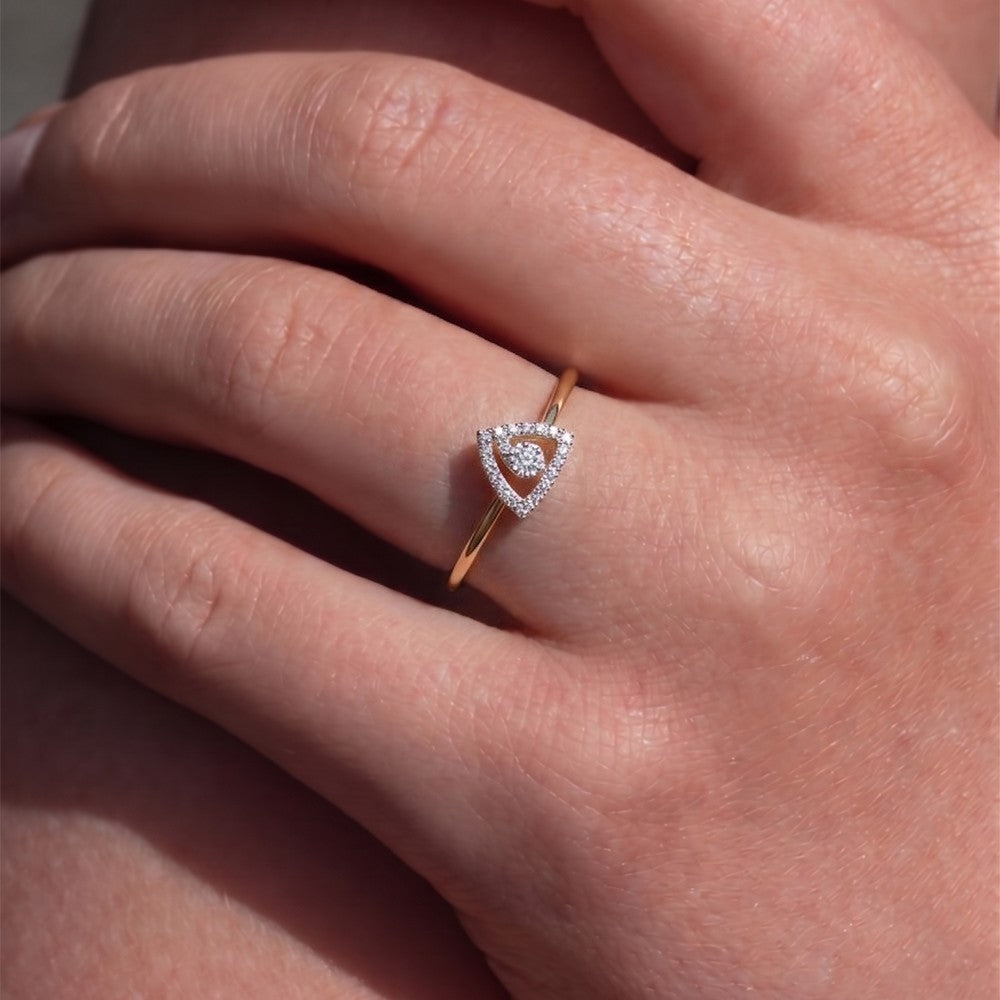 Gold ring with a triangle-shaped center and diamond accents on a person's finger.