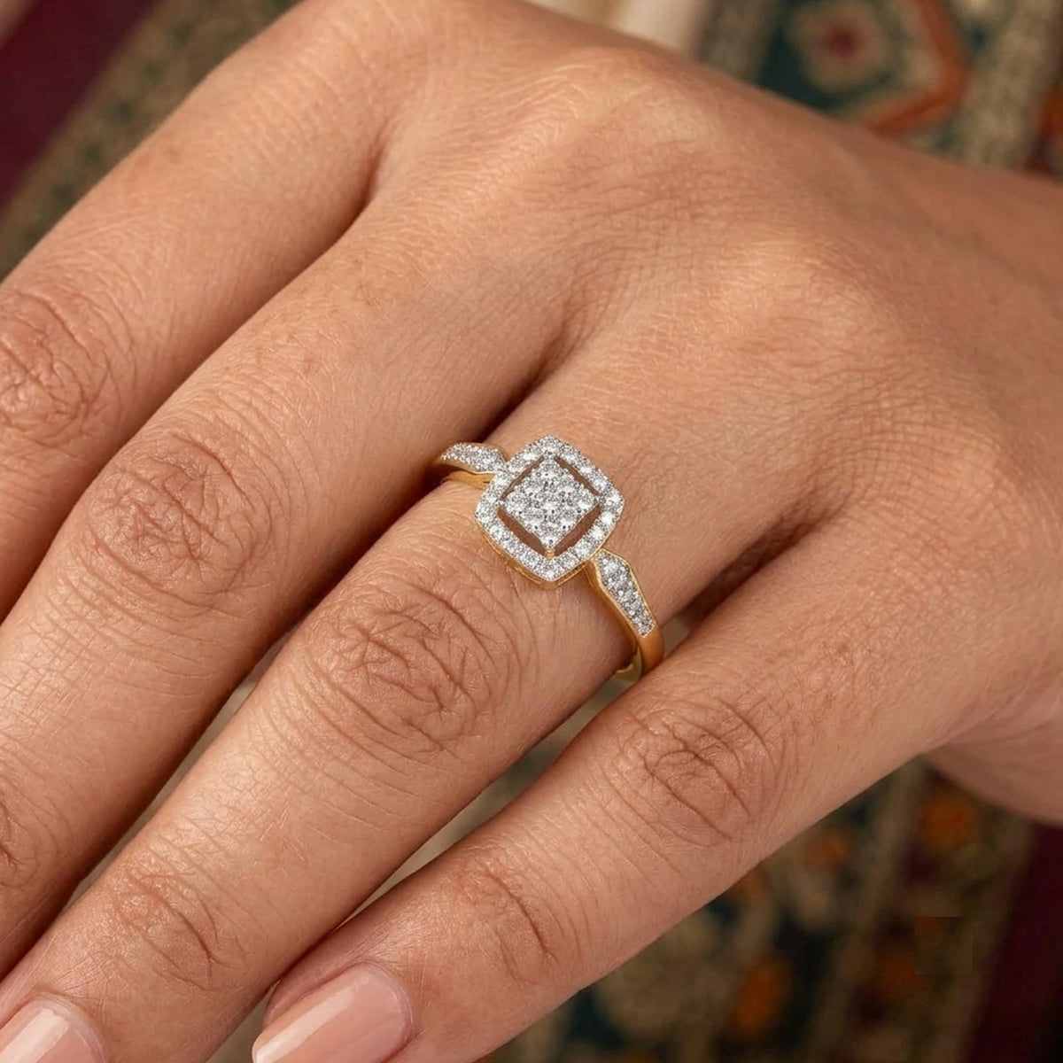Gold ring featuring a square-shaped pavé diamond cluster with a halo design, shown on a person's finger.