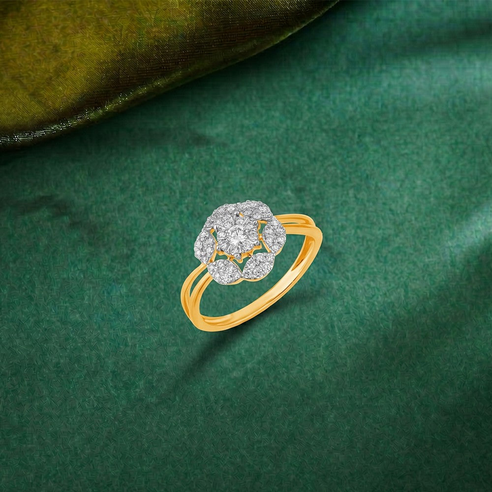 Gold ring featuring a floral-shaped cluster of pavé diamonds, set against a green surface.